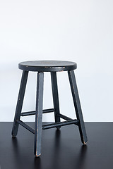 Image showing Black shabby stool on wooden surface