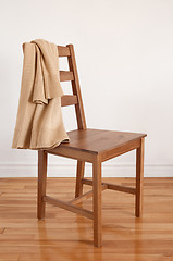 Image showing Chair on wooden floor with clothing put over its back