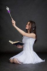 Image showing Girl in suit of the fairy with magic wand on black background