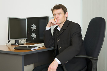 Image showing Young businessman sits at table
