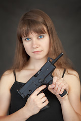 Image showing Serious beauty armed with submachine gun on a black