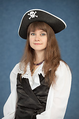 Image showing Beautiful young girl in a pirate hat on blue background