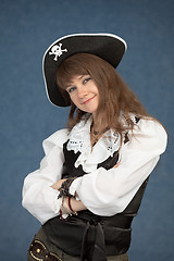 Image showing Beautiful young girl in a pirate hat on blue background