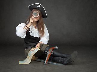 Image showing Beautiful girl the pirate looks through a magnifier