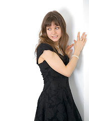 Image showing Young girl in a dress has nestled on white wall