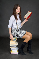 Image showing Beautiful young woman reads on a pile of books on black backgrou