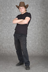 Image showing Young guy in cowboy hat standing on a grey background