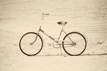 Image showing Ancient bicycle on beach - retro sepia