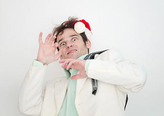 Image showing Amusing man in white suit and christmas cap is frightened