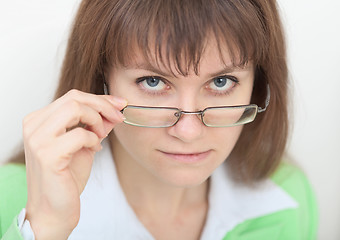 Image showing Strict young woman looks at us over eyeglasses