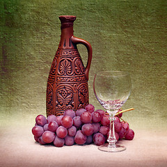 Image showing Still-life with clay bottle, glass and grapes against canvas