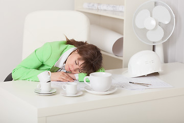 Image showing Businesswoman  sleeps sitting at table on workplace