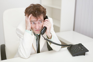 Image showing Frightened guy speaks by phone at office