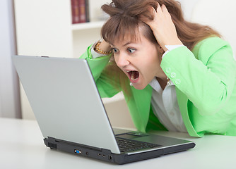 Image showing Young girl shouts looking in laptop screen