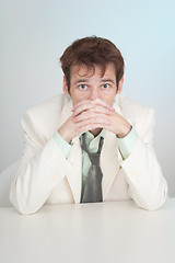 Image showing Young sorrowful person in white suit sits at table