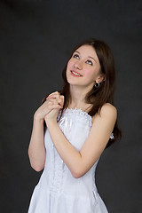 Image showing Pensive beautiful girl in white dress on black background