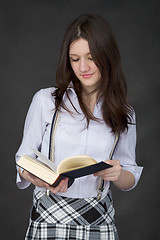 Image showing Beautiful young woman reads big book on black background