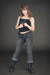 Image showing Young girl in jeans with an automatic pistol in hands