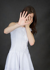 Image showing Girl cover face with hands on black background