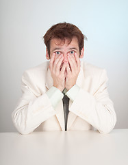 Image showing Young sorrowful people in white suit sits at table