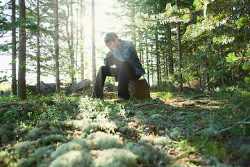 Image showing Sad young man sits in wood on stone