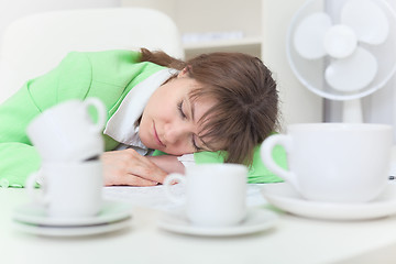 Image showing Woman has got tired and sleeps on table among coffee cups