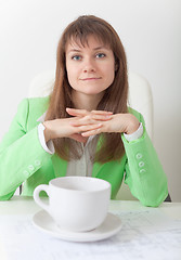 Image showing Young woman sits at table with big cup of coffee