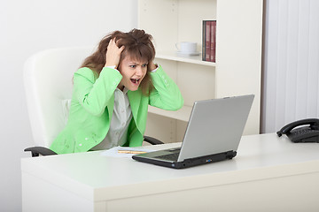 Image showing Emotional young woman on workplace with laptop