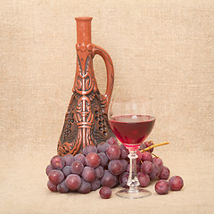 Image showing Still-life with clay bottle, grapes and glass on canvas backgrou