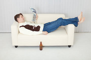 Image showing Person comfortably lie on sofa with beer and journal