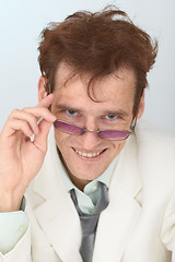 Image showing Cheerful tousled guy looks over eyeglasses