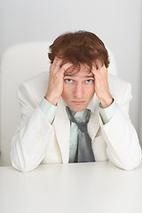 Image showing Sad young businessman sits at a table