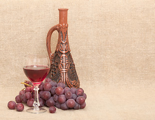 Image showing Clay bottle, grapes and glass on canvas background