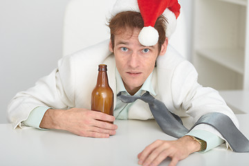 Image showing Young man in Christmas hat at office with a beer bottle