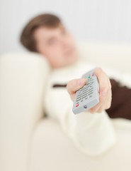 Image showing Man lying on sofa uses remote control