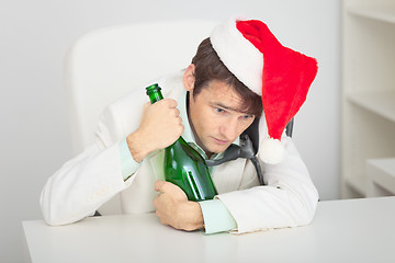 Image showing Young guy in Christmas cap with a bottle