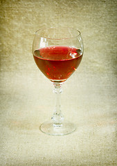 Image showing One glass with red wine against brown drapery