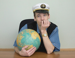 Image showing Young man in a sea cap of captain with globe