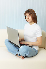 Image showing Young girl with laptop sits on sofa