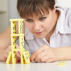 Image showing Young woman accurately builds tower of dominoes