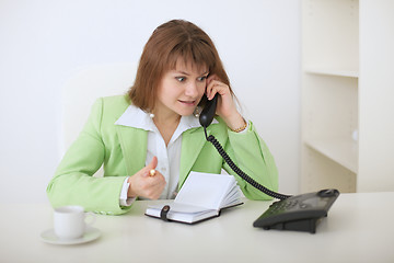 Image showing Young beautiful woman - secretary emotionally speaks on phone