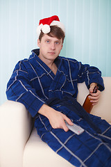 Image showing person in christmas hat sits on sofa with beer