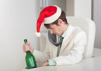 Image showing Drunken man in Christmas cap with bottle in a hand