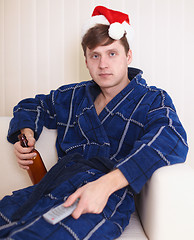 Image showing Person in christmas hat sits on sofa with beer