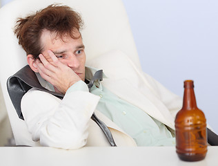 Image showing Young sad businessman sits with an empty bottle