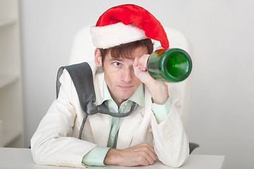 Image showing Amusing guy in Christmas cap with bottle in a hand