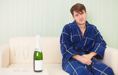 Image showing Guy in expectation of woman with sparkling wine on sofa