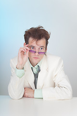 Image showing Tousled young man in eyeglasses sitting at a table