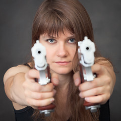 Image showing Serious girl aims from two pistols close up