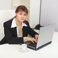 Image showing Young beautiful woman with laptop sits at a table